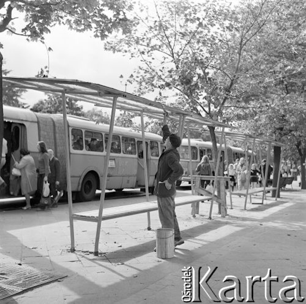 Autobusy komunikacji miejskiej na przystanku, na pierwszym planie mężczyzna malujący wiatę.
Fot. Jarosław Tarań, zbiory Ośrodka KARTA [73-182]
