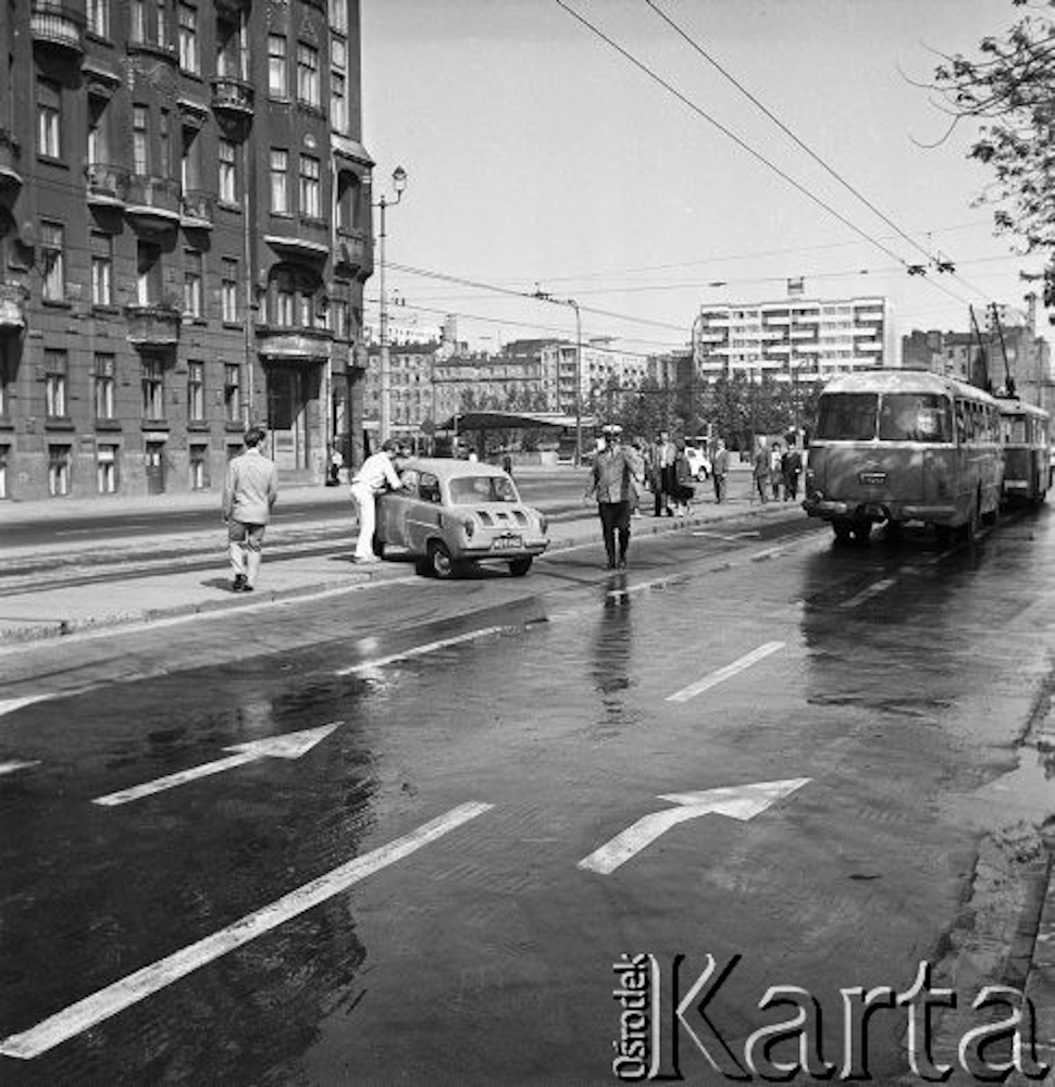 Uliczna stłuczka, samochód osobowy stojący na środku ulicy, w tle policjant oraz tłum ludzi i jadący autobus oraz trolejbus.
Fot. Jarosław Tarań, zbiory Ośrodka KARTA
